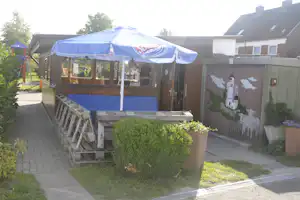 Campingplatz Krautsand am Elbstrand - Restaurant auf dem Campingplatz mit Sitzgelegenheiten und Sonnenschirm im Freien