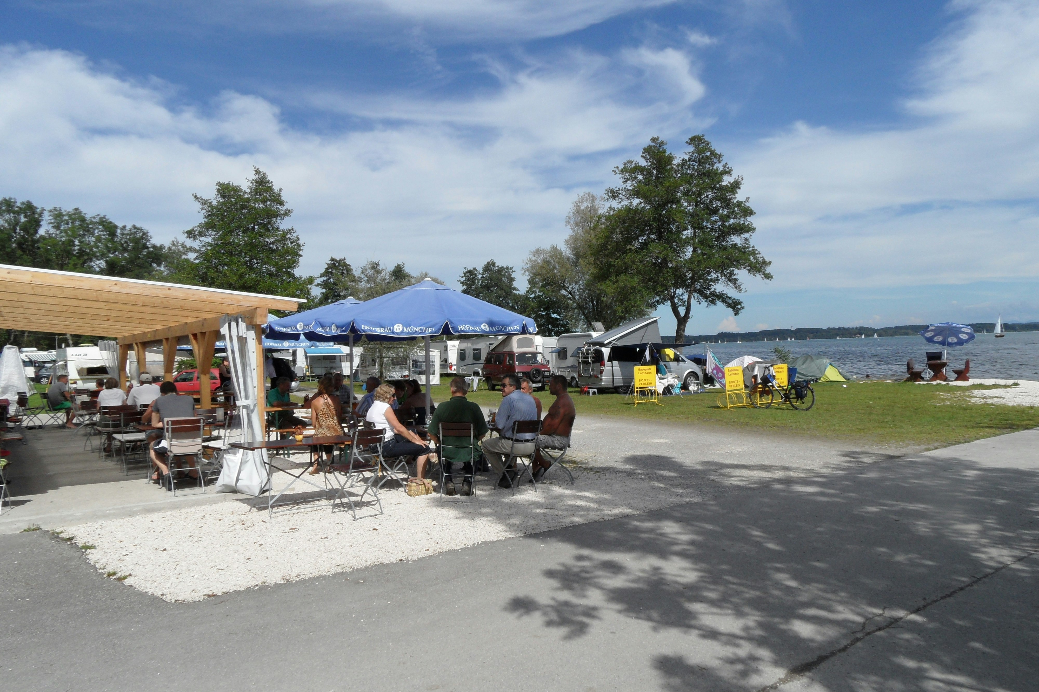 Chiemsee Camping Lambach  -  Camper auf der Terrasse vom Restaurant auf dem Campingplatz mit Blick auf den Chiemsee