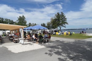 Chiemsee Camping Lambach - Camper auf der Terrasse vom Restaurant auf dem Campingplatz mit Blick auf den Chiemsee