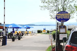 Chiemsee Camping Lambach - Einfahrt vom Campingplatz mit Terrasse vom Restaurant am See