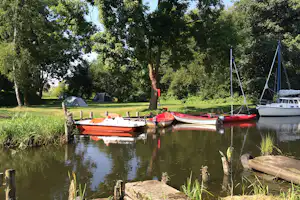 Campingplatz Lassan - Zeltwiese im Schatten unter Bäumen und Bootsanleger am Campingplatz