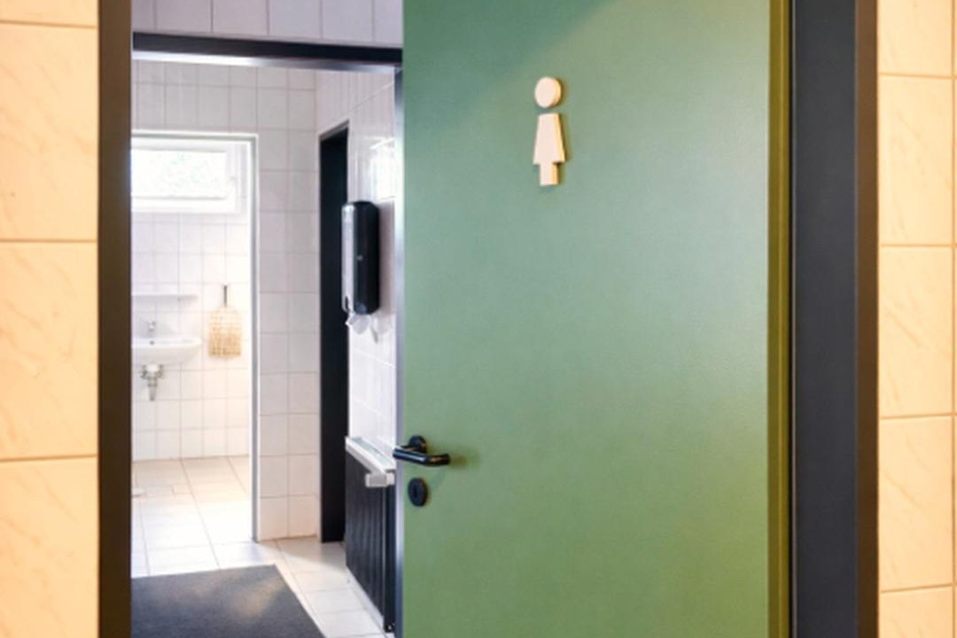 Geöffnete Eingangstür mit Blick in den Flur, Fliesenboden und Kacheln an den Wänden.