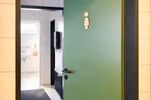 Geöffnete Eingangstür mit Blick in den Flur, Fliesenboden und Kacheln an den Wänden.