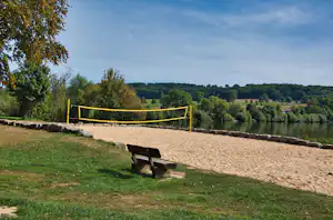 Boule-Bahn auf einem Campingplatz mit Bank am Rand, umgeben von Rasen, Hecken und Bäumen in der Landschaft.