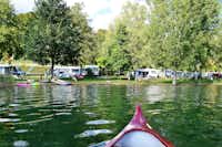 Campingplatz Schachenhorn - der  Wohnwagen- und Zeltstellplatz zwischen Bäumen, von einem Kanu aus aufgenommen