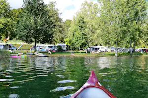 Campingplatz Schachenhorn - der Wohnwagen- und Zeltstellplatz zwischen Bäumen, von einem Kanu aus aufgenommen