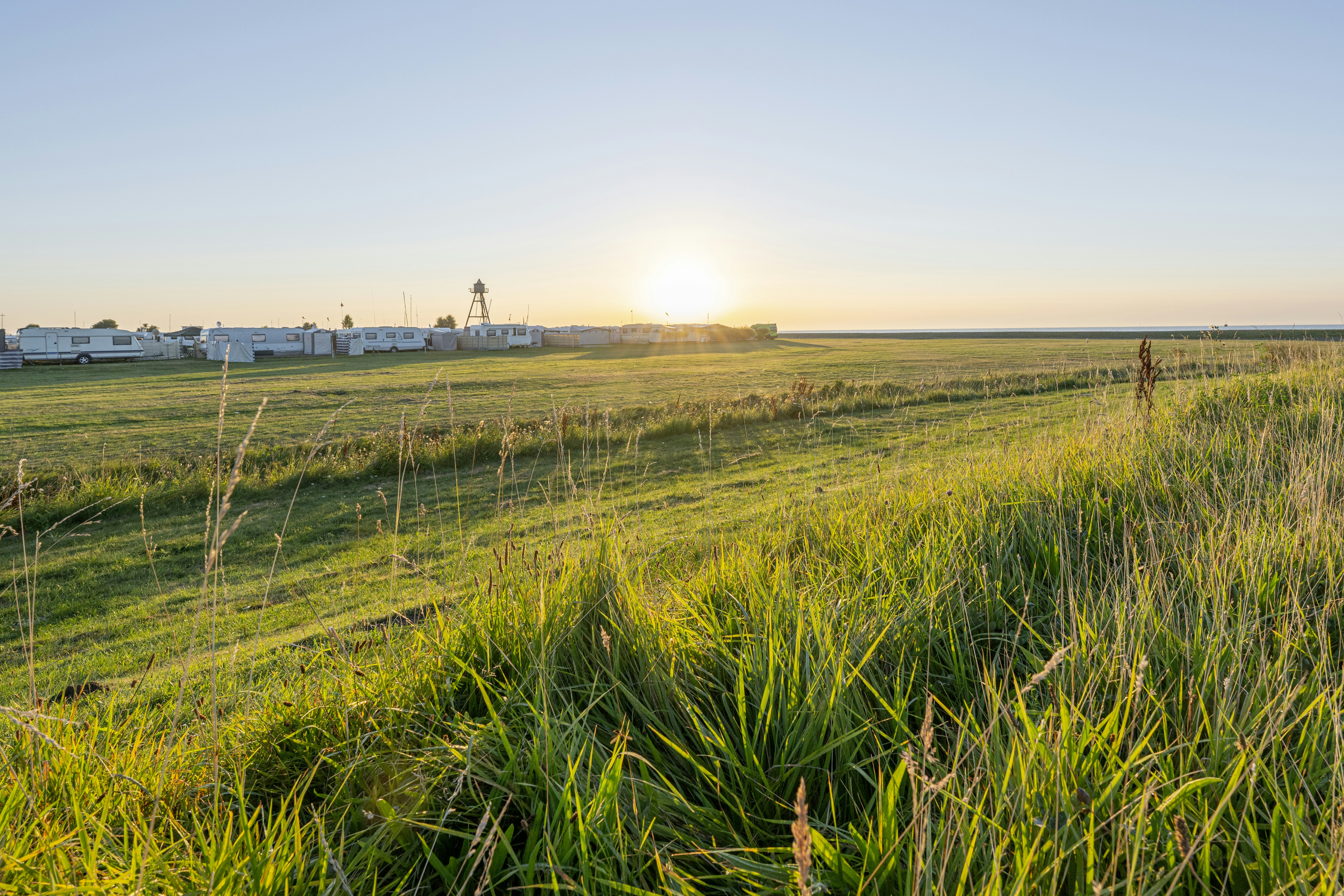 Campingplatz Schillig - Blick vom grünen Feld auf den Campingplatz bei Sonnenuntergang