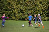 Campingplatz Südstrand  - Fußball spielende Kinder auf grüner Wiese vom Campingplatz