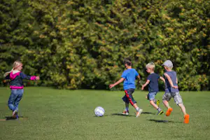 Campingplatz Südstrand - Fußball spielende Kinder auf grüner Wiese vom Campingplatz