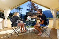 Campéole Le Lac  -  Camper auf der Veranda vom Mobilheim auf dem Campingplatz mit Blick auf die Alpen