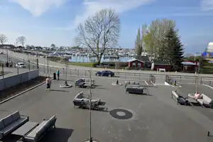 Terrasse am Campingplatz mit Sitzmöbeln, Blick auf den Hafen und viele Boote an den Stegen.