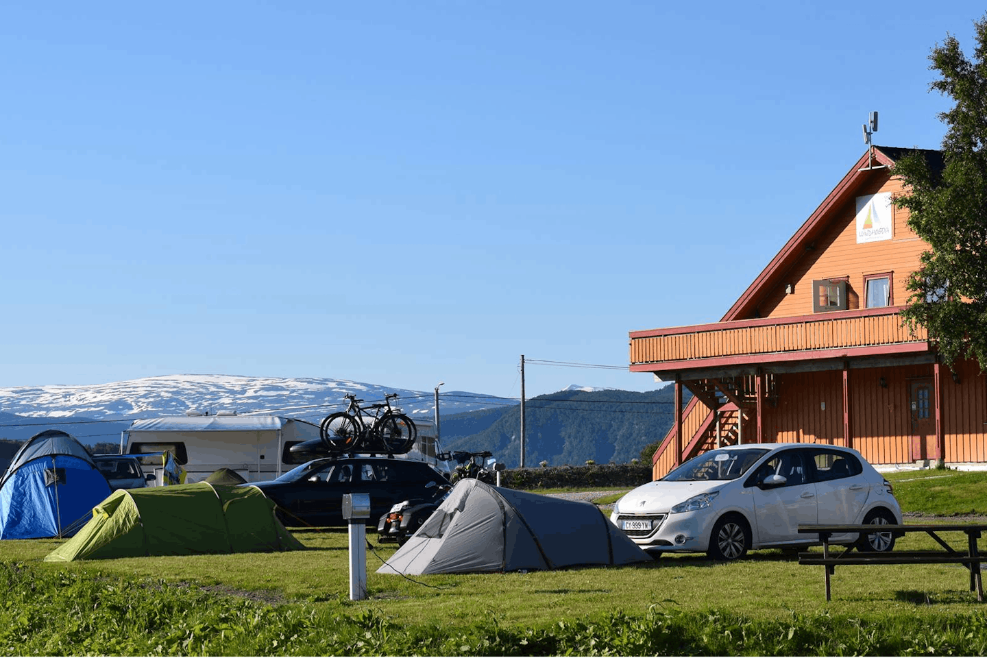 Campotel Fauske -  Rezeption, Zeltstellplätze und Wohnwagenstellplätze im Grünen auf dem Campingplatz mit Blick auf die Berge