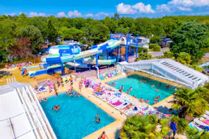 Großer Camping-Pool mit Wasserrutschen, Liegen und mehreren Becken, umgeben von Bäumen und Wegen.