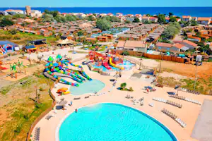 Luftaufnahme eines Campingplatzes mit großem Pool, Wasserrutschen, Spielbereich und vielen Wohnmobilen und Bungalows in der Anlage.