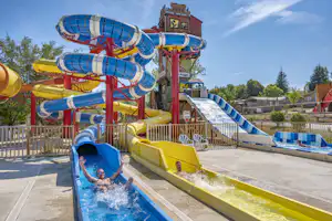 Bunte Wasserrutschen im Campingbereich mit mehreren Bahnen, blauen und gelben Rutschen sowie Becken mit Wasser.
