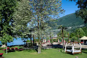 Caravan Camping Miralago - Liegestühle und Sonnenschirme vom Campingplatz mit Blick auf den Langensee