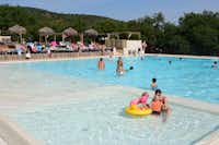 Castel Camping Domaine de la Bergerie - Gäste schwimmen im Pool, spielen mit Kindern im Planschbecken und genießen die Sonne auf den Liegestühlen auf dem Campingplatz