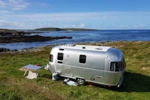 Clifden Eco Beach Camping & Caravanning Park - Wohnwagen auf grüner Wiese vom Campingplatz mit Blick auf den Atlantik in Irland