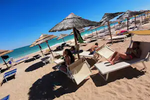 Costa Verde Camping Village - Gäste am Badestrand mit Liegestühlen und Sonnenschirmen