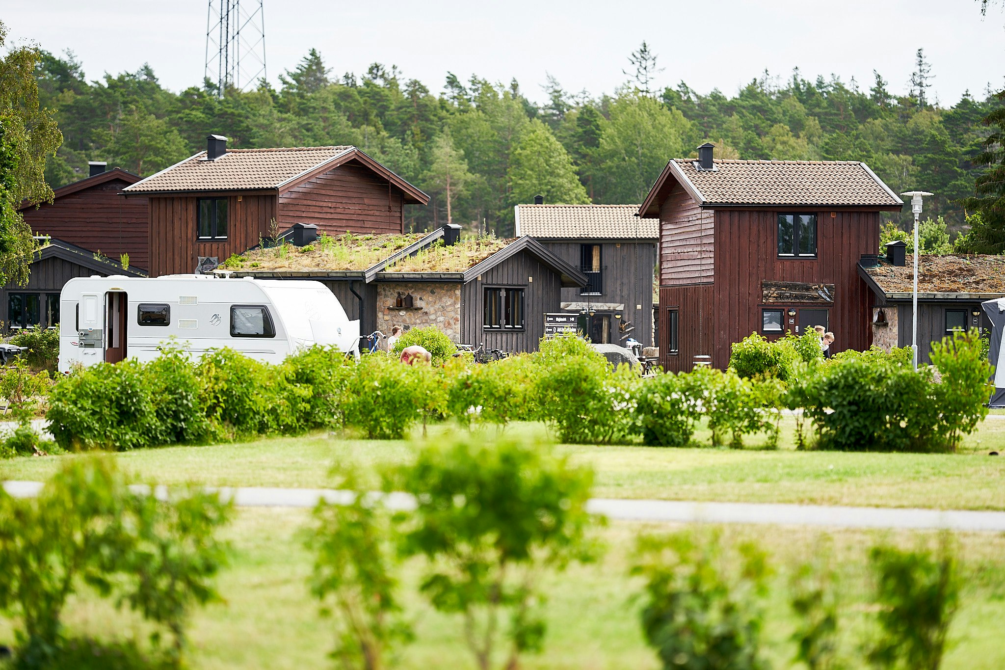 Daftö Resort - Blick auf durch leichten Heckenbewuchs voneinander abgetrennte Standplätze und das aus Mietunterkünften bestehende Camping Village Piratbyn
