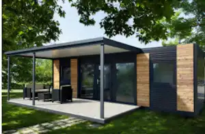 Moderner Camping-Bungalow mit Holzverkleidung, großer Glasfront und Terrasse, Sitzbank und Tisch im Schatten der Überdachung.