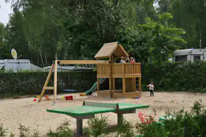 DCC-Campingplatz Berlin-Kladow - Kinderspielplatz auf dem Campingplatz mit Klettergerüst, Rutsche und Schaukel und einer Tischtennisplatte im Vordergrund