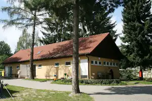 DCC-Campingplatz Gatow - Das Sanitärgebäudes von aussen zwischen Bäumen