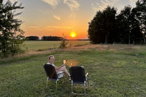 De Weidewei - Camperin sitzt auf einem Stuhl auf der Wiese