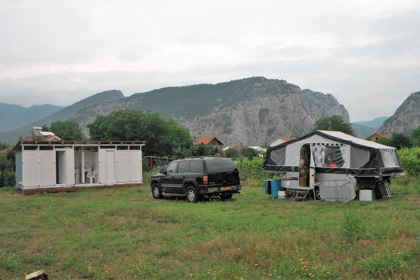 Rock Land Camp  -  Wohnwagen und Sanitärgebäude auf dem Stellplatz vom Campingplatz mit Blick auf die Berge