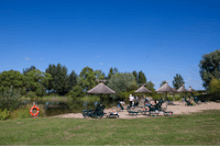Domaine Les Bois du Bardelet  -  Strand vom Campingplatz am See mit Sonnenschirmen und Liegestühlen
