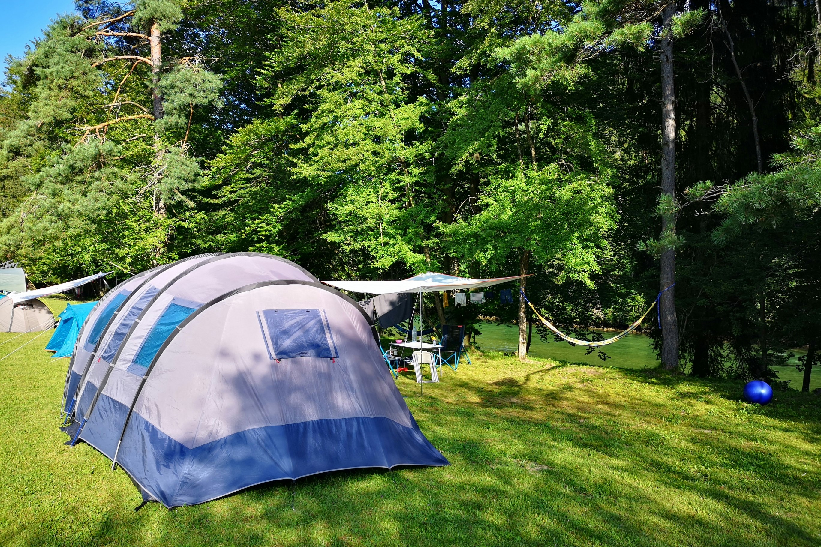 ECO River Camp - Zeltplatz auf der Wiese umgeben von Bäumen