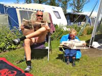 Elite Camp Løkken Klit - Camper sitzen vor dem Wohnmobil in der Sonne