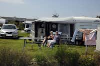Elite Camp Løkken Klit - vor dem Wohnmobil sitzen Camper in der Sonne