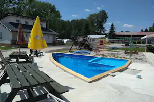 Euro Air Camp - Pool mit Sitzgelegenheiten und Spielplatz im Hintergrund
