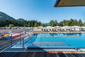 Euro-Camp Wilder Kaiser - Pool vom Campingplatz mit Sonnenschirmen und Liegestühlen und mit Blick aufBerge