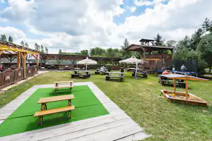 Eurocamp Holiday Park Liščí Farma - Sitzgelegenheiten auf dem Campingplatz mit Trampolin und Sandkasten für Kinder, im Hintergrund ein Bistro