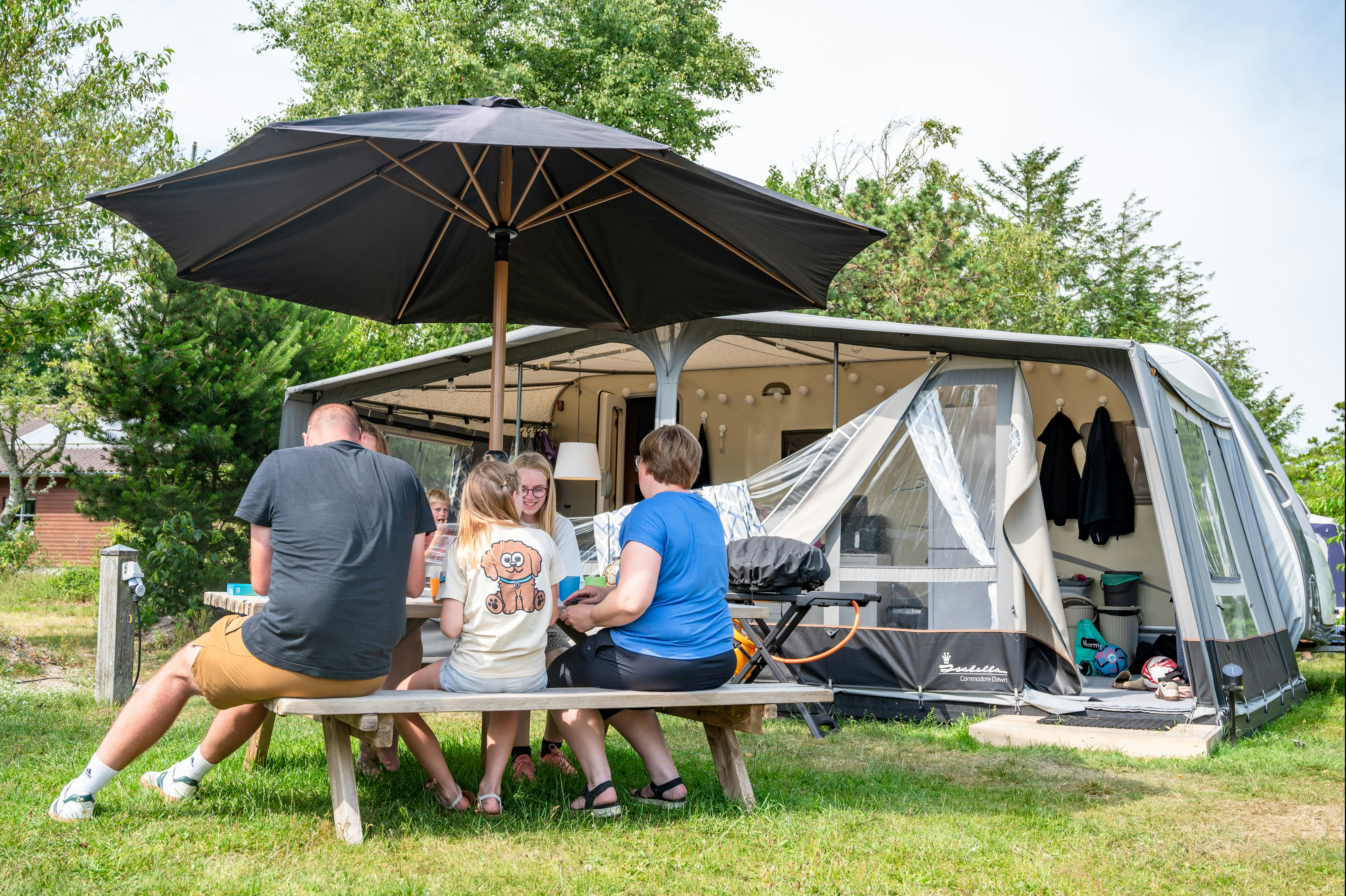 Familie Camping Nymindegab - Familie sitzt an einem Tisch auf ihrem Standplatz