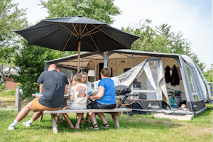 Familie Camping Nymindegab - Familie sitzt an einem Tisch auf ihrem Standplatz