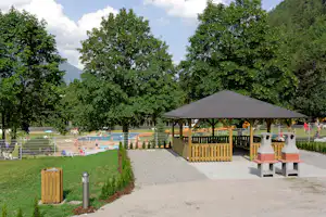 Familiencamping Oberdrauburg - Grillstelle und überdachte Picknicktische vom Campingplatz mit Blick auf den Poolbereich