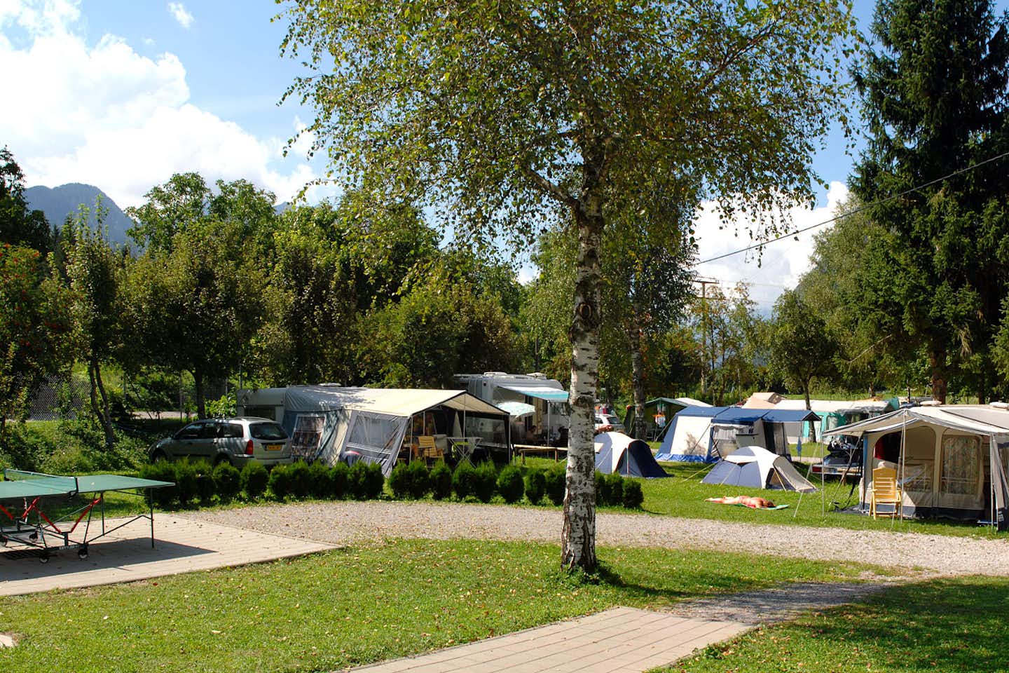 Familiencamping Oberdrauburg - Wohnwagen- und Zeltstellplatz vom Campingplatz zwischen Bäumen mit Blick auf die Berge