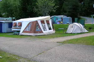 Großes Zelt und weiteres Campingzelt auf einer Wiese am Campingplatz, mit Bäumen im Hintergrund.
