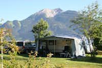 Feriencenter Biberhof - Wohnwagen mit Vorzelt auf dem Campingplatz mit einem Berg der Alpen im Hintergrund