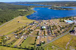 Luftaufnahme eines Campingplatzes am See mit Stellplätzen, Wegen, Bäumen und Uferlinie im grünen Tal.