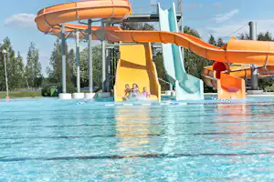 Wasserpark am Campingplatz: orange und blaue Wasserrutsche über dem Pool mit spritzendem Wasser.