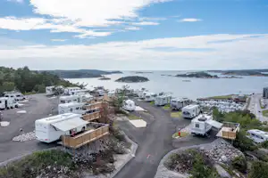 Campingplatz mit Wohnwagen und Stellplätzen, Blick auf das Meer und mehrere Inseln in der Ferne.