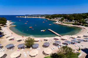 FKK-Camping Valalta - Badestrand beim Campingplatz mit Liegestühlen und Sonnenschirmen