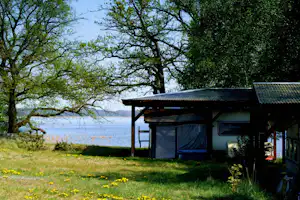 FKK Ferienidyll am Rätzsee - Stellplatz im Schatten unter Bäumen mit Seeblick auf dem Campingplatz