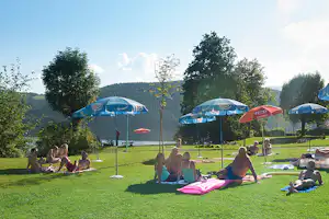 FKK & Textil Terrassencamping Pesenthein - Gäste auf der Wiese mit Blick auf den Millstätter See