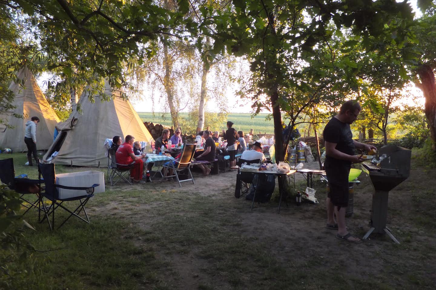 Flaeming Camping Oehna - Camper beim gemeinsamen Grillen und Essen vor Tipi Zelten
