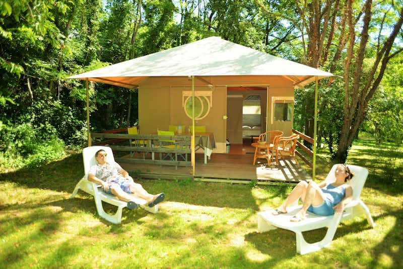 Camping Cœur d'Ardèche - Mobilheim vom Campingplatz mit Veranda, Esstischen und Liegestühlen zwischen Bäumen